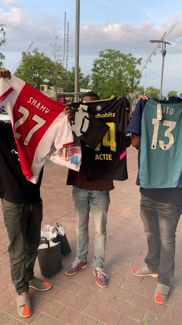 Drie vrienden tonen trots hun gepersonaliseerde voetbalshirts van YSTHEPLUQQ op straat